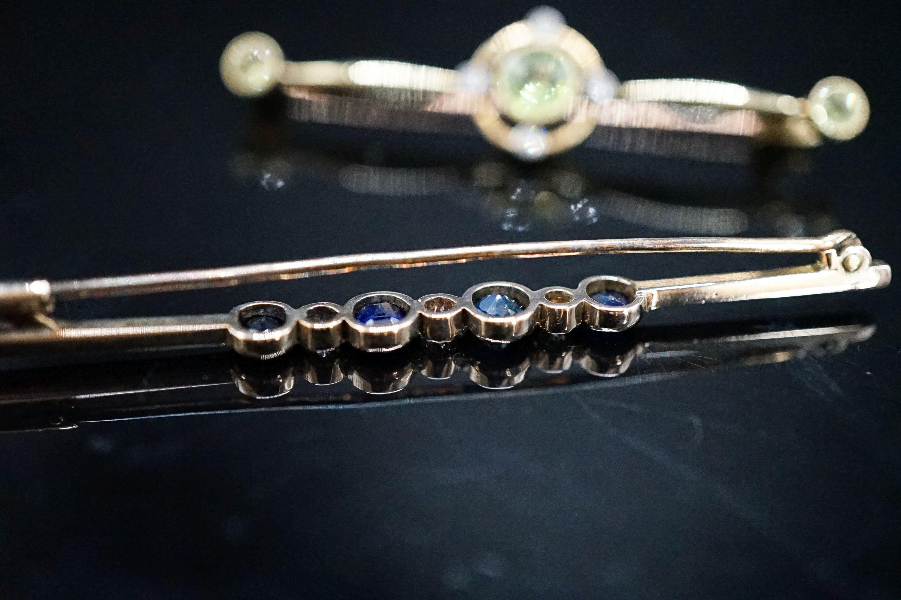 An Edwardian 15ct, peridot and diamond set bar brooch, 49mm, gross weight 4.4 grams and a yellow metal, sapphire and diamond set seven stone bar brooch, gross 3 grams